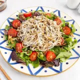 Deliciosa ensalada de gulas con tomates cherry y hojas verdes, servida en un plato decorado.