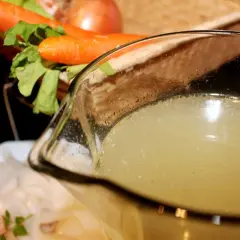 Un delicioso caldo de pescado casero, listo para usar en tu próxima receta. Zanahorias y apio en el fondo.
