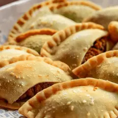 Una bandeja llena de empanadas de pollo doradas y crujientes, listas para disfrutar.