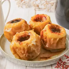 Cuatro manzanas asadas en freidora de aire, con el centro relleno de canela y azúcar, listas para disfrutar.