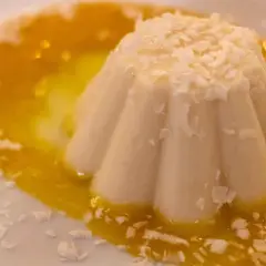 Delicioso helado de coco con salsa de mango y coco rallado, un postre tropical que te transporta al paraíso.