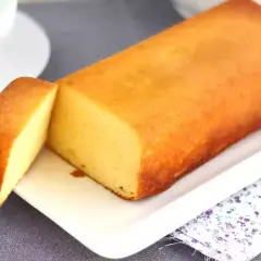 Un delicioso bizcocho de leche condensada, dorado y esponjoso, servido en una bandeja blanca con una porción cortada.