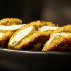 Arepas de choclo doradas y crujientes, rellenas de queso blanco fresco, servidas en un cuenco de barro.