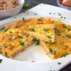 Tortilla de atún dorada y esponjosa, espolvoreada con perejil fresco. Un plato sencillo y delicioso.