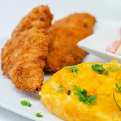 Crujiente solomillo de pollo empanado, puré de zanahoria y ensalada de tomate y cebolla.