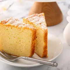 Dos porciones de pa de pessic, esponjoso y espolvoreado con azúcar glas, junto a frutos rojos y un tenedor.