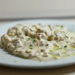 Deliciosa brandada de bacalao cremosa, espolvoreada con perejil fresco y un toque de aceite de oliva.