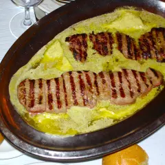 Filetes a la parrilla bañados en una cremosa salsa de mantequilla y hierbas, un plato que evoca el sabor de un café parisino.