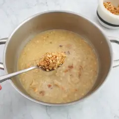 Cuchara con trozos de almendras listas para añadir a la olla, creando una deliciosa salsa de almendras.