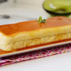 Un delicioso flan de manzana rectangular, cubierto de caramelo dorado y decorado con una ramita verde.