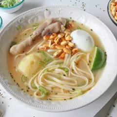 Un reconfortante caldo de gallina peruano con fideos, huevo duro, papa, choclo y un toque de limón.