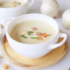 Crema reconfortante de cebolla, adornada con picatostes crujientes y perejil fresco.