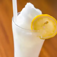 Un refrescante granizado de limón, coronado con una rodaja de limón fresco, listo para disfrutar en un día caluroso.