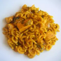 Fideuà de pollo con fideos rizados y trozos de pollo en salsa dorada, servida en plato blanco.