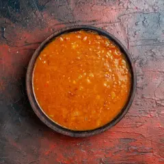 Un tazón de salsa emmy que lleva, con trozos de tomate y especias, sobre una superficie rústica.