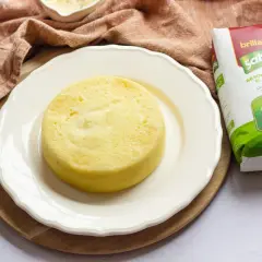 Pastel de arroz amarillo, esponjoso y redondo, servido en plato blanco junto a un paquete de arroz Sabroz.
