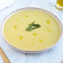 Deliciosa crema de esparragos trigueros, servida en un cuenco con un chorrito de aceite de oliva y espárragos frescos.