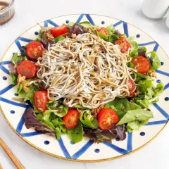 Deliciosa ensalada de gulas con tomates cherry y hojas verdes, servida en un plato decorado.