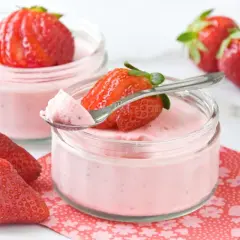 Delicioso mousse de fresa en vasitos, decorado con fresas frescas y una cucharita lista para probar.