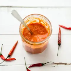Tarro de salsa piri piri casera con chiles rojos alrededor. ¡Lista para dar sabor!
