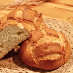 Pan de queso recién horneado, con una miga esponjosa y trozos de queso derretido visibles.
