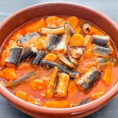 Un cuenco de barro con un sabroso all i pebre, un guiso tradicional de anguilas y patatas en salsa roja.