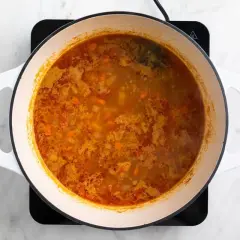 Olla con garbanzos y acelgas hirviendo, con trozos de zanahoria y especias.