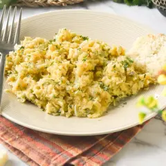 Un plato de bacalao a bras, desmenuzado y mezclado con patatas y perejil, servido con una rebanada de pan.