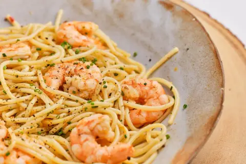 Espaguetis con gambas, un plato delicioso y fácil de preparar. La pasta se mezcla con gambas jugosas y se espolvorea con cebollino fresco.