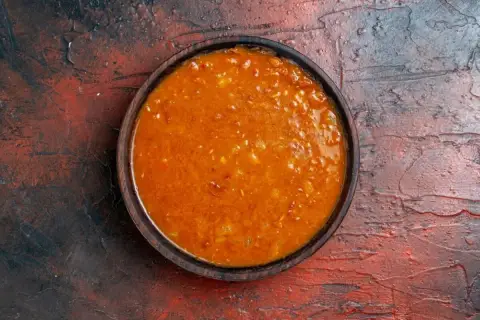 Un tazón de salsa emmy que lleva, con trozos de tomate y especias, sobre una superficie rústica.