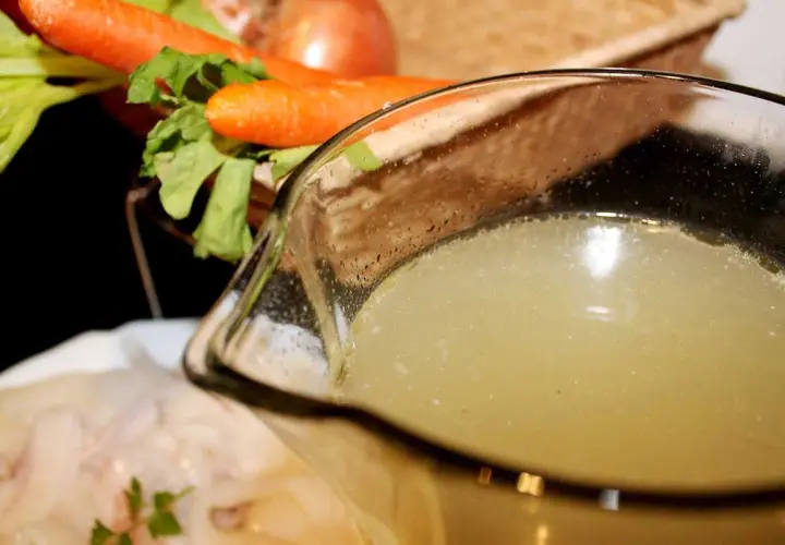 Un delicioso caldo de pescado casero, listo para usar en tu próxima receta. Zanahorias y apio en el fondo.