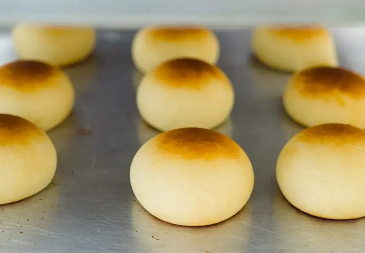 Pan de bono recién horneados, dorados y esponjosos, listos para disfrutar.
