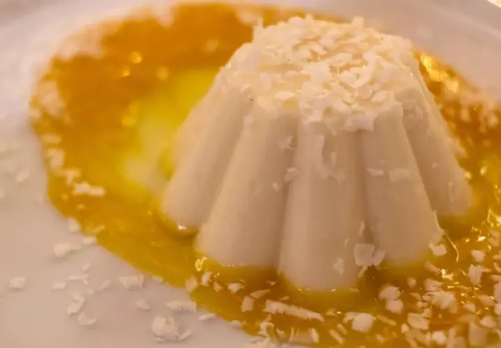 Delicioso helado de coco con salsa de mango y coco rallado, un postre tropical que te transporta al paraíso.