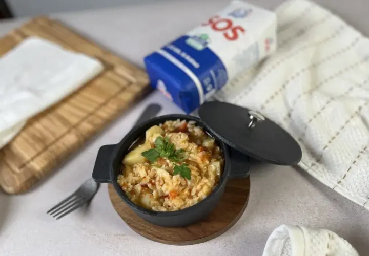 Delicioso arroz con bacalao servido en cazuela negra, listo para disfrutar.