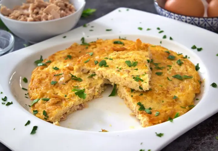 Tortilla de atún dorada y esponjosa, espolvoreada con perejil fresco. Un plato sencillo y delicioso.