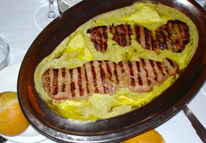Filetes a la parrilla bañados en una cremosa salsa de mantequilla y hierbas, un plato que evoca el sabor de un café parisino.