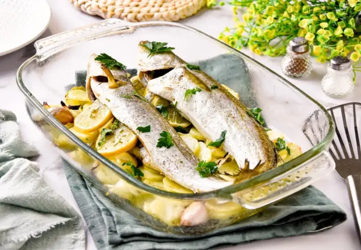 Pescadilla al horno con patatas, limón y ajo, recién salida del horno. Un plato sencillo y delicioso.