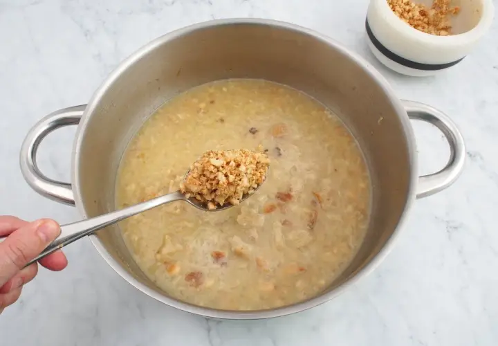 Cuchara con trozos de almendras listas para añadir a la olla, creando una deliciosa salsa de almendras.
