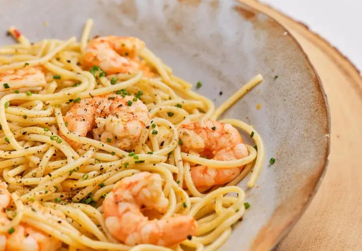 Espaguetis con gambas, un plato delicioso y fácil de preparar. La pasta se mezcla con gambas jugosas y se espolvorea con cebollino fresco.