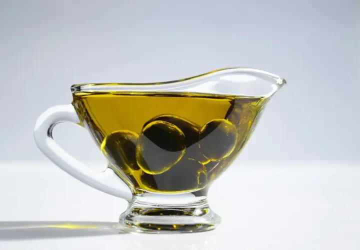 Aceite de oliva para el pelo en una salsera de cristal con aceitunas. Un ingrediente natural para un cabello radiante.