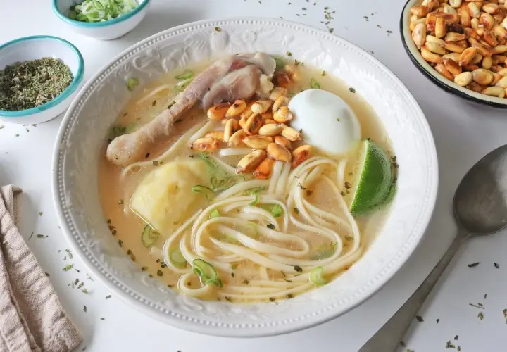 Un reconfortante caldo de gallina peruano con fideos, huevo duro, papa, choclo y un toque de limón.