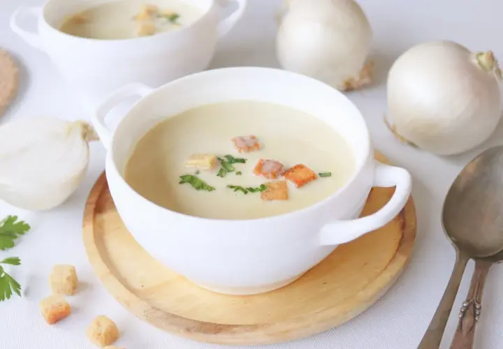 Crema reconfortante de cebolla, adornada con picatostes crujientes y perejil fresco.
