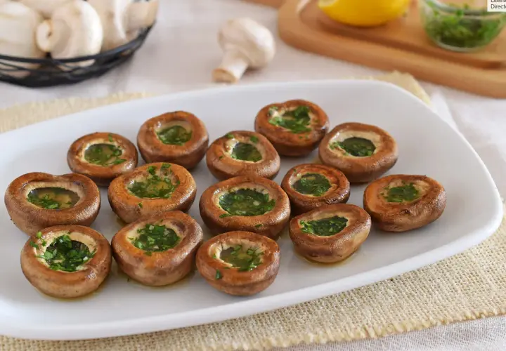 Champiñones a la plancha, dorados y rellenos de perejil fresco, listos para disfrutar.