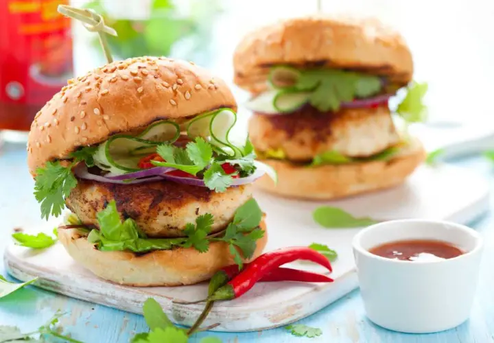 Deliciosa hamburguesa de pollo con pepino, cebolla morada y cilantro fresco. Un toque picante con chiles rojos.