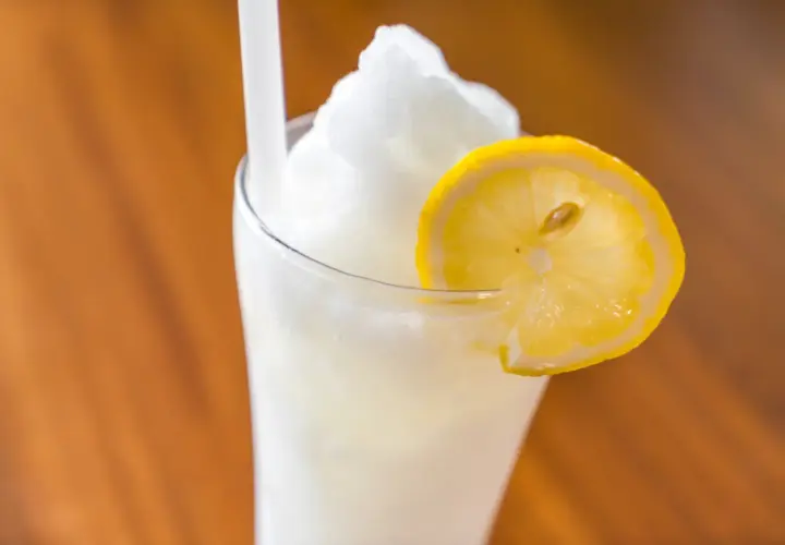 Un refrescante granizado de limón, coronado con una rodaja de limón fresco, listo para disfrutar en un día caluroso.