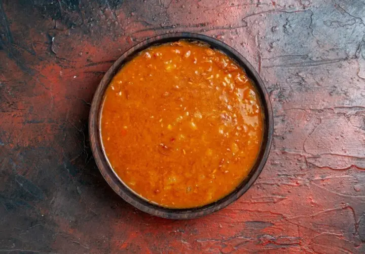 Un tazón de salsa emmy que lleva, con trozos de tomate y especias, sobre una superficie rústica.