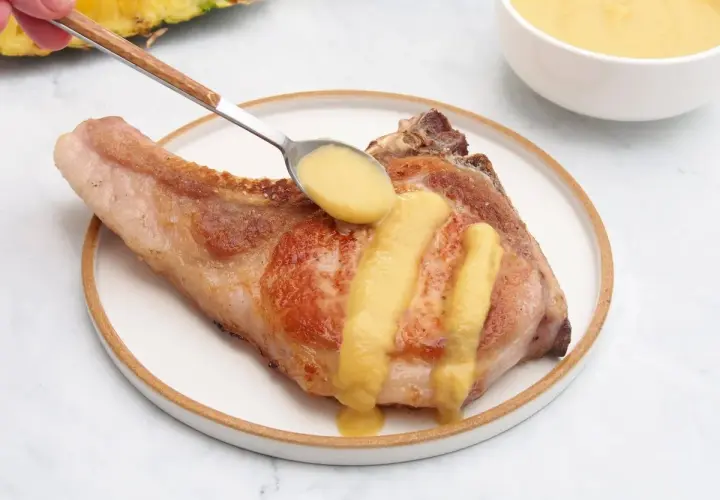 Chuleta de cerdo servida con una deliciosa salsa de piña, que realza su sabor.