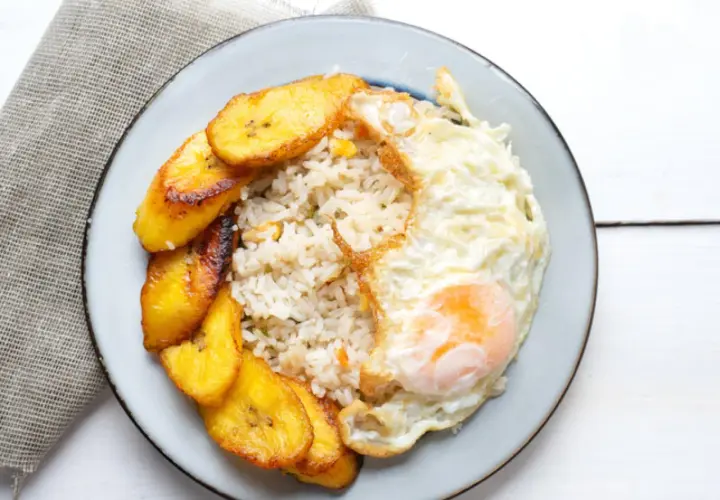 Plato de arroz a la cubana con huevo frito y plátanos maduros fritos.