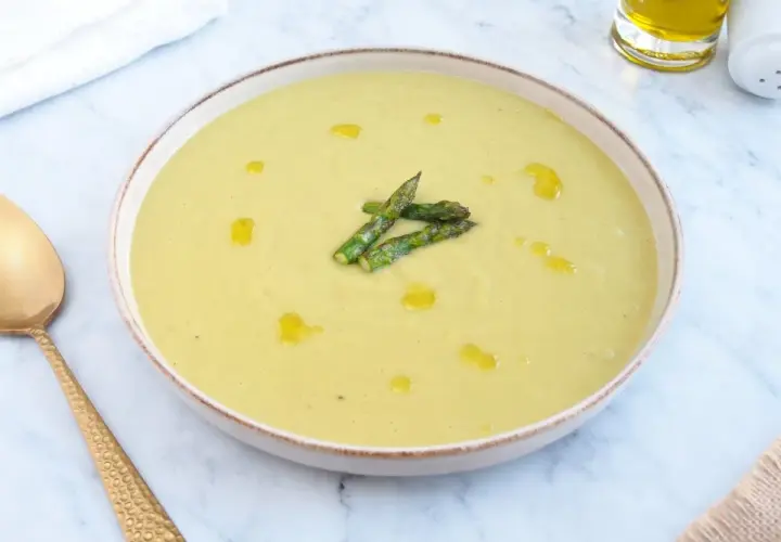 Deliciosa crema de esparragos trigueros, servida en un cuenco con un chorrito de aceite de oliva y espárragos frescos.