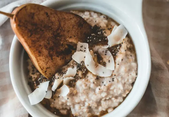 Delicioso porridge de avena con pera, coco rallado y semillas de chía. Un desayuno saludable y nutritivo.